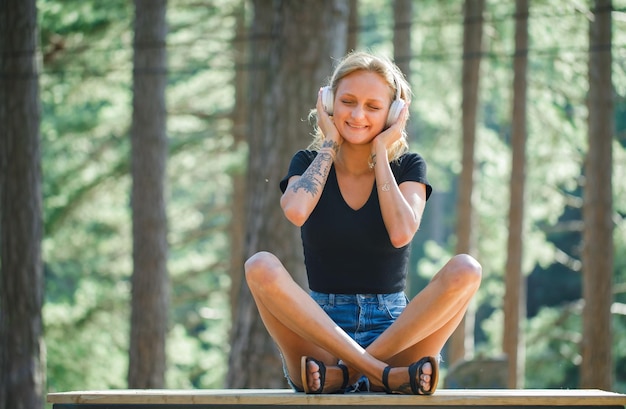 Blondes Mädchen mit Kopfhörer wünscht sich auf Naturhintergrund