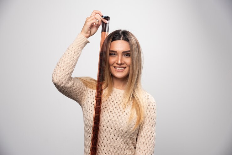 Kostenlose Foto blondes mädchen prüft fotos auf fotorolle und fühlt sich glücklich und positiv über das ergebnis.