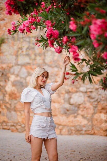 Blondes Mädchen schaut weg, indem es ein Baumblatt auf Steinhintergrund hält