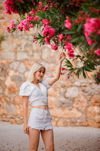 Blondes Mädchen schaut weg, indem es ein Baumblatt auf Steinhintergrund hält