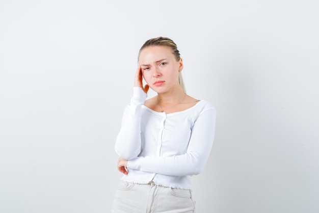 Blondes Mädchen scheint nachdenklich auf weißem Hintergrund