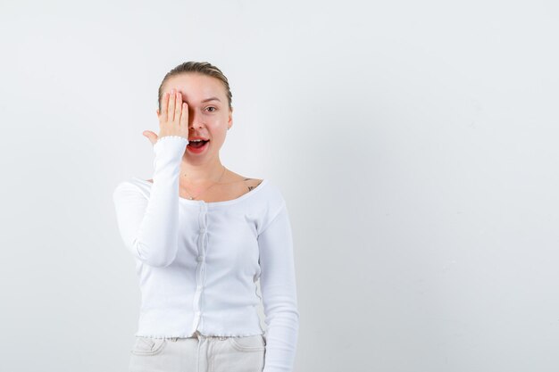 Blondes Mädchen schließt ihr Auge auf weißem Hintergrund