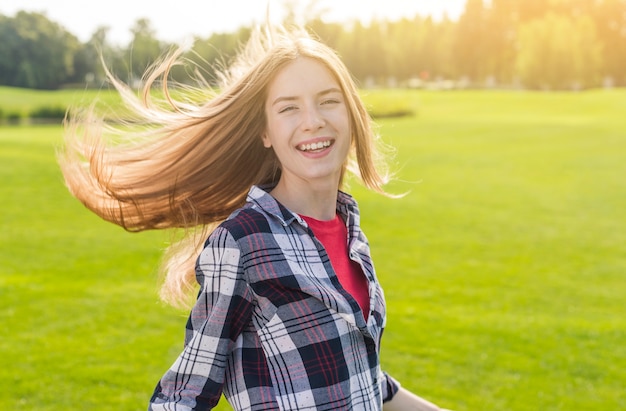 Blondes mädchen, welches die kamera an einem sonnigen tag betrachtet