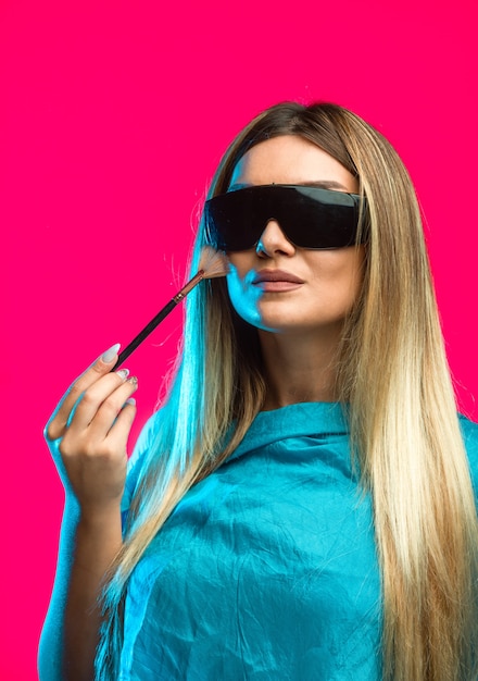 Blondes Model mit schwarzer Sonnenbrille und Kosmetik.