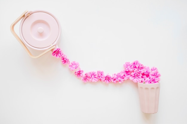 Kostenloses Foto blumen, die von der teekanne in schale fließen