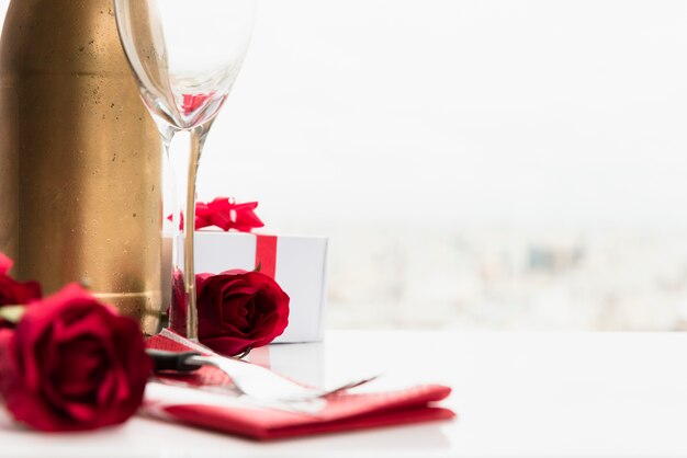 Blumen in der Nähe von Glas, Geschenk und eine Flasche zu trinken