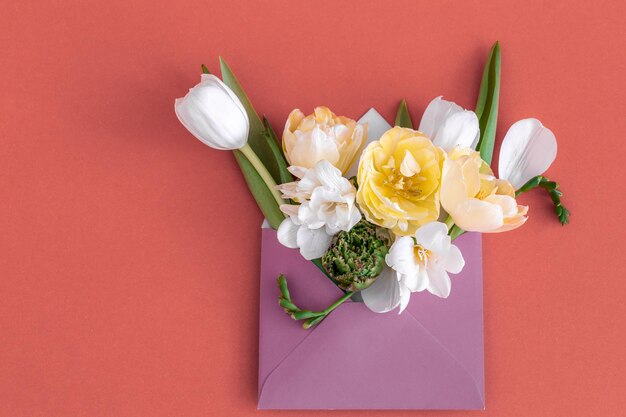 Blumen in einem Umschlag auf einem farbigen Hintergrund liegen flach