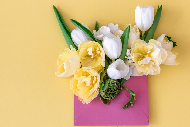 Blumen in einem Umschlag auf einem farbigen Hintergrund liegen flach