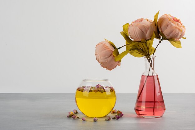 Blumen in Glasvase und Tasse grüner Tee auf grauem Tisch.