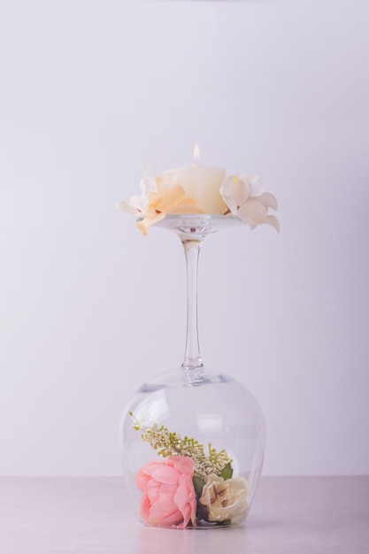 Blumen in Weinglas und Kerze.