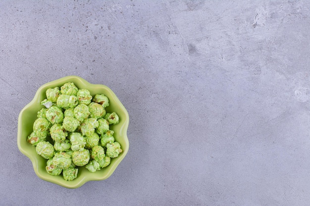 Blumenförmige Schüssel mit einem bescheidenen Haufen von mit Süßigkeiten überzogenem Popcorn auf Marmorhintergrund. Foto in hoher Qualität