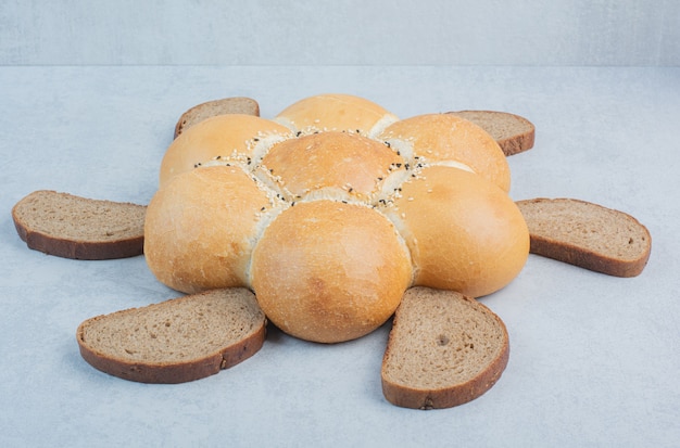 Blumenförmiges Brot und Brotscheiben auf weißem Hintergrund. Hochwertiges Foto