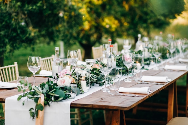 Blumengirlande aus Eukalyptus und rosa Blumen liegt auf dem Tisch