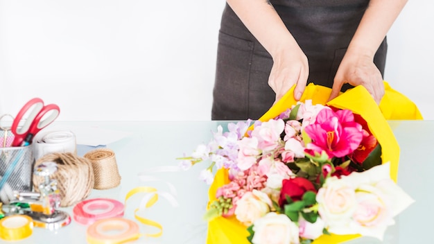 Blumenhändlerhand, die Blumen im gelben Stoff einwickelt