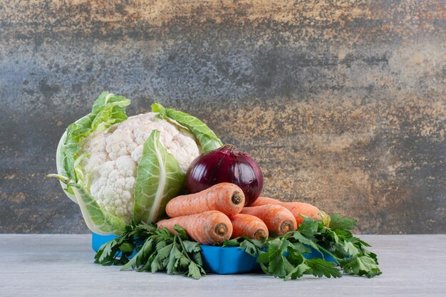 Blumenkohl, Karotten und Zwiebeln auf blauem Teller. Hochwertiges Foto