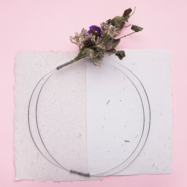 Blumenstrauß auf rundem Ring über dem Papier auf rosa Hintergrund