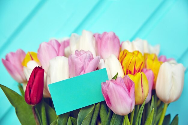 Blumenstrauß aus frischen mehrfarbigen Tulpenblumen auf altem blauem Holztisch