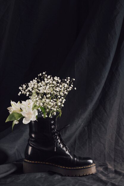 Blumenstrauß aus weißen Blüten im dunklen Lederstiefel