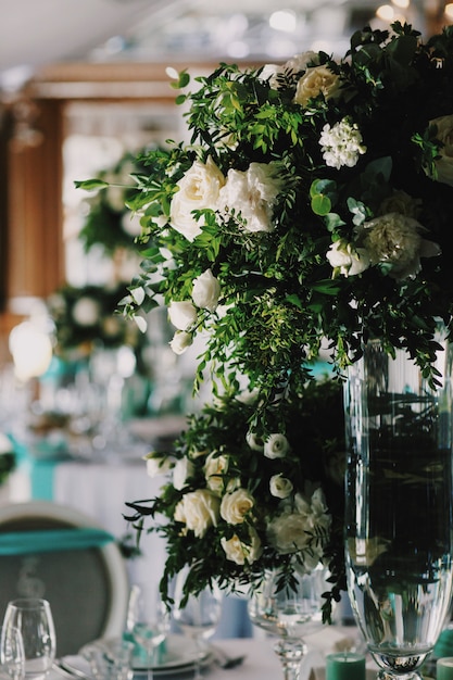 Blumenstrauß aus weißen Rosen steht in der Mitte des Tisches im Restaurant