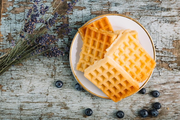 Blumenstrauß in der Nähe von Waffeln und Blaubeeren