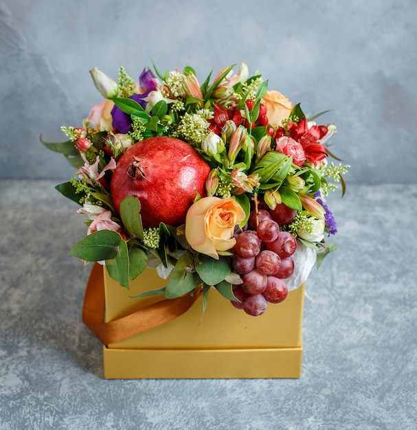 Blumenstrauß mit Granatapfel, Traube in gelber quadratischer Schachtel