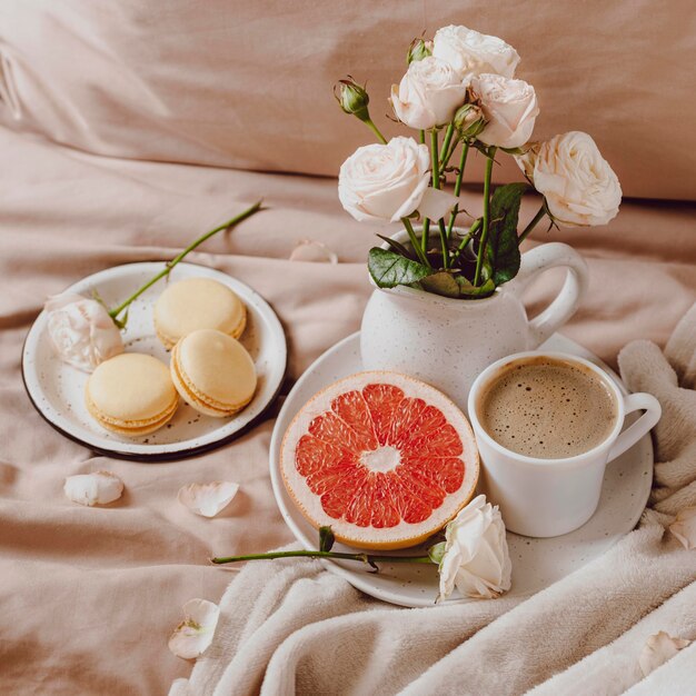 Blumenstrauß mit Morgenkaffee und Grapefruit auf dem Bett