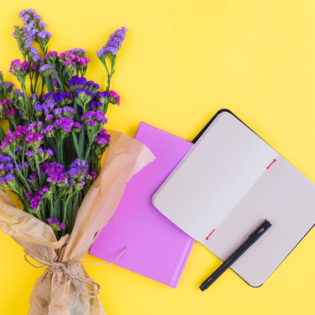Blumenstrauß; Tagebücher und Stift auf gelbem Hintergrund