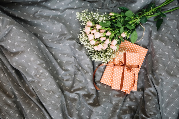 Blumenstrauß und Geschenke, die auf Bett liegen