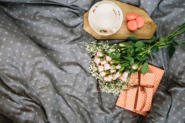 Blumenstrauß und Geschenke nahe Cup und Nachtisch