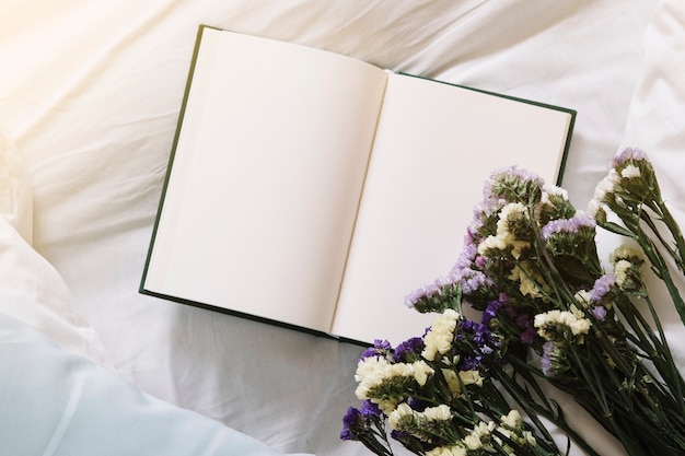 Blumenstrauß und Notizbuch auf Bett