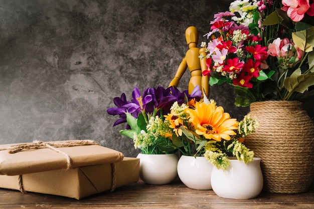 Blumenvasen mit hölzerner blinder Zahl und Geschenkboxen auf Holztisch