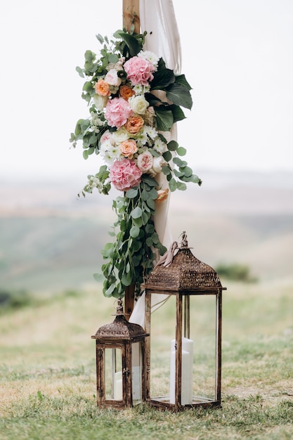 Blumenzusammensetzung draußen gemacht vom Eukalyptus und von den zarten rosa Blumen mit Kerzen