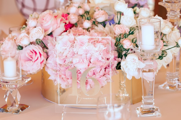 Blumenzusammensetzung und transparente Glasgravurplatte zwischen Kerzen