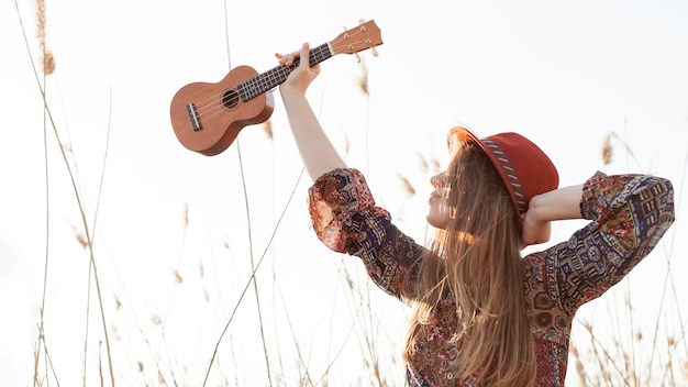 Kostenloses Foto böhmische frau hält ukulele und posiert