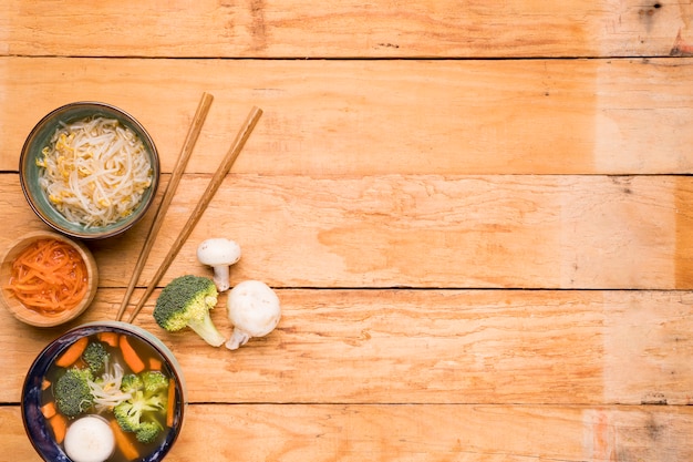 Bohnen sprießen; Karotte; und Fischballsuppe mit Stäbchen auf Holztisch