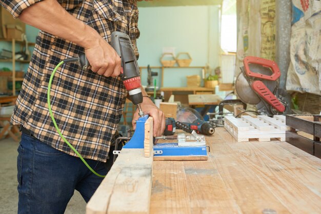 Bohrende Holzarbeit des geernteten Mannes in einer Werkstatt