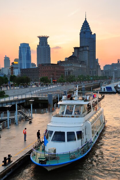 Boot im Fluss Huangpu mit urbaner Architektur von Shanghai bei Sonnenuntergang im Dock