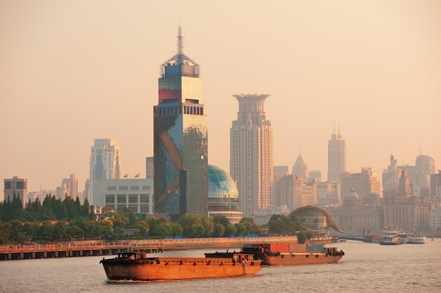Boot im Fluss Huangpu mit urbaner Architektur von Shanghai bei Sonnenuntergang