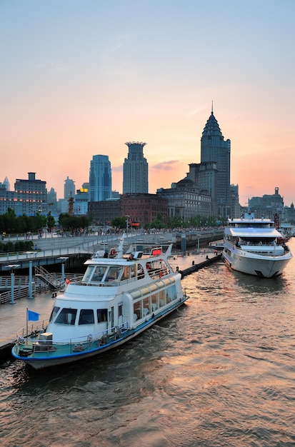 Boot im Fluss Huangpu mit urbaner Architektur von Shanghai bei Sonnenuntergang