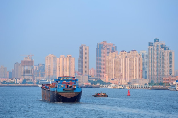 Boot im Fluss Huangpu mit urbaner Architektur von Shanghai