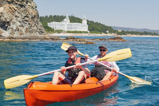 Boot Kajakfahren in der Nähe von Klippen an einem sonnigen Tag. Kajak fahren in einer ruhigen Bucht. Erstaunliche Aussichten. Reise-, Sportkonzept. Lebensstil. Eine glückliche Familie.