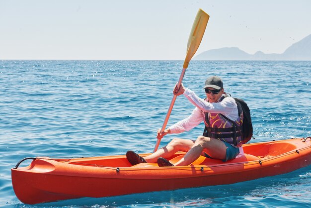 Boot Kajakfahren in der Nähe von Klippen an einem sonnigen Tag. Reise-, Sportkonzept. Lebensstil.