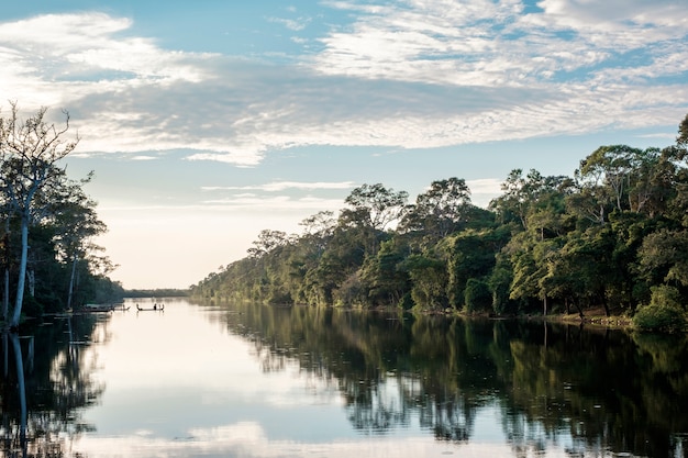 Boot, Wald, Fluss und blauer Himmel in der Reflexion