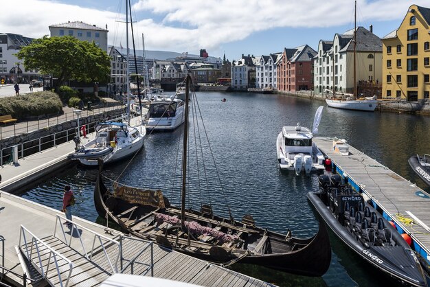 Boote auf einem breiten Wasserkanal, umgeben von bunten Gebäuden in Alesund, Norwegen