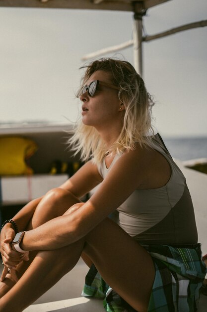 Bootsfahrt auf Bali. Eine junge Frau mit Sonnenbrille segelt auf einem Boot zu einer nahe gelegenen Insel.