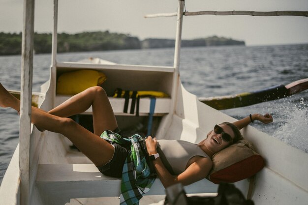 Kostenloses Foto bootsfahrt auf bali. eine junge frau mit sonnenbrille segelt auf einem boot zu einer nahe gelegenen insel.