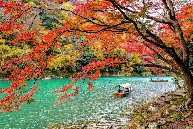 Bootsmann, der das Boot am Fluss stochert. Arashiyama in der Herbstsaison entlang des Flusses in Kyoto, Japan.