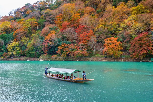Bootsmann, der das Boot am Fluss stochert. Arashiyama in der Herbstsaison entlang des Flusses in Kyoto, Japan.