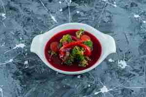 Kostenloses Foto borschsuppe in einer schüssel, auf dem blauen hintergrund.