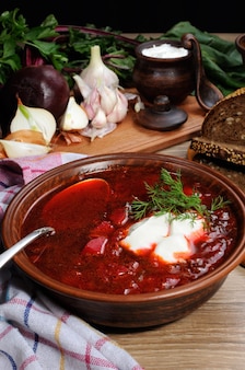 Borschtschgemüse-rote-bete-suppe mit scheiben roggengetreidebrot und sauerrahm-knoblauch-kräuter